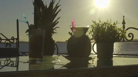 Multiple cocktails on a table with sun setting into the sea in the background Stock Footage 140054306