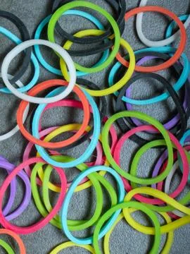 Multiple colored rubberbands in a pile on a gray textured background 스톡 사진