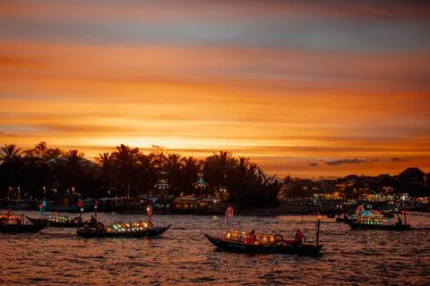 Multiple colorful lantern boats floating on the river against a glowing tropical Stock-Fotos
