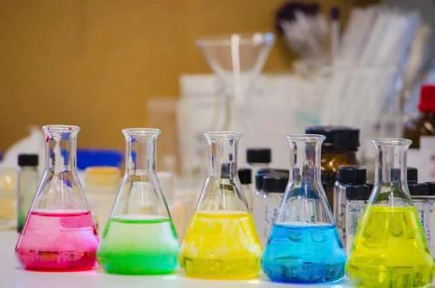 Multiple colorful solution in conical flask lined on a bench in a chemistry l Stock Photos