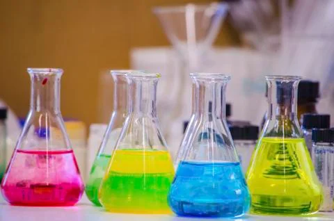 Multiple colorful solution in conical flask on a bench in a chemistry lab wit Stock Photos