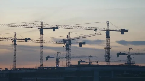 Multiple construction cranes rising against dusk sky Video stock 309978807