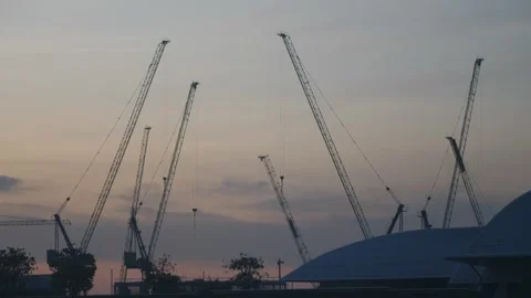 Multiple construction cranes rising against dusk sky Stock Footage 309978816