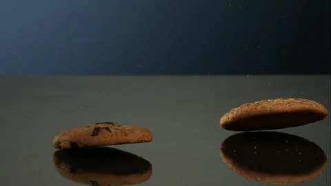 Multiple Cookies Falling And Bouncing Across A Reflective Dark Surface Stock Footage 326291668