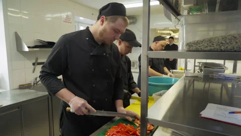 Multiple Cooks are Slicing the red peppers and tomatoes for Fast Food Production Video stock 157517702