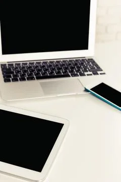 Multiple digital devices on a clean workspace, emphasizing modern technology Stock Photos
