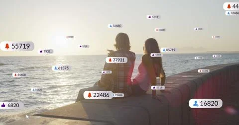 Multiple digital icons with increasing numbers over caucasian couple sitting Fotos Stock