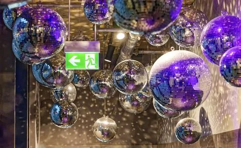Multiple disco balls hanging from ceiling with colorful reflections and exi.. Stock Photos