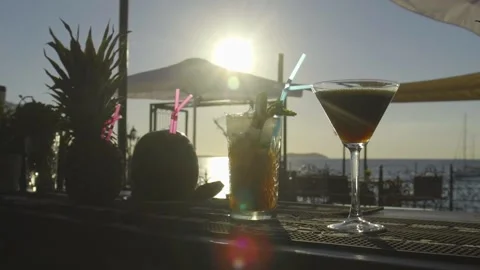 Multiple drinks on a bar with sun setting into the sea in the background Stock Footage 140050734