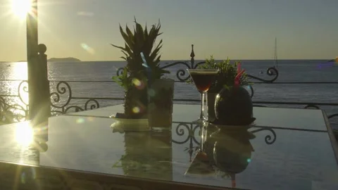 Multiple drinks on a table with sun setting into the sea in the background Stock Footage 140054787