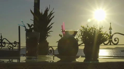 Multiple drinks on a table with sun setting into the sea in the background Stock-Footage 140055795
