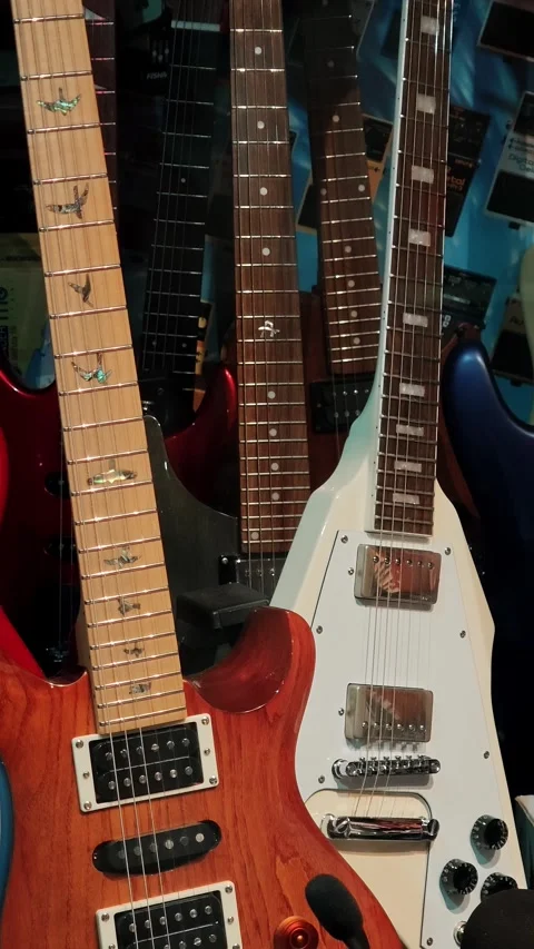 Multiple electric guitar necks with strings displayed in retail store Stock Footage 334633598