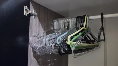 Multiple empty clothes hangers hanging inside a modern wooden bedroom closet Stock Photos