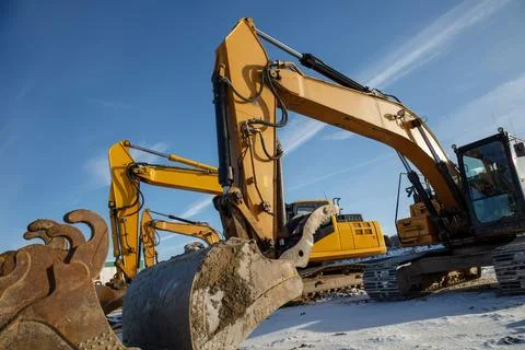 Multiple excavators operating on a construction site in winter conditions. Stock-Fotos
