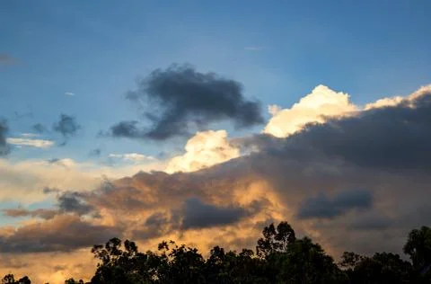 Multiple exposure of a cumulus cloud filling half the sky at sunset, over the Stock Photos