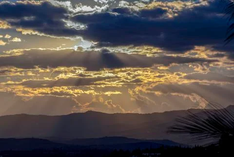 Multiple exposure of the sun hiding behind some dense clouds at the begining  Foto stock