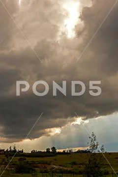 Multiple exposure of the sunbeams brighting through dense cumulus clouds, ove Stock Photos