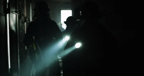 Multiple firefighters walk down hallway with flashlights Stock Footage 91148389