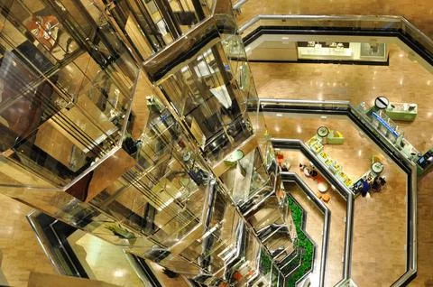 Multiple floors connected with a glass elevator tower Stock Photos