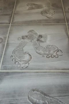 Multiple footprints coming and going through grout Stock Photos