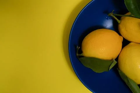 Multiple fresh lemons on a blue plate with copy space Stock Photos