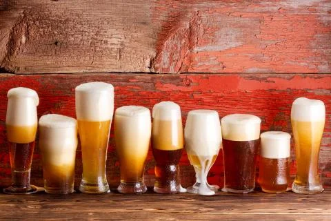 Multiple frothy beer pints on rustic wooden bench Stock Photos