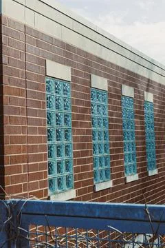 Multiple glass block windows on a brick wall of a building with a blue fenc.. Stock Photos