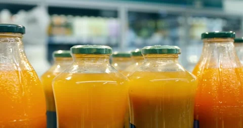 Multiple glass bottles with vibrant orange juice neatly positioned on Stock Footage 309046821
