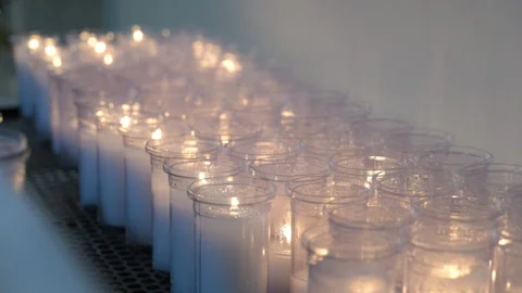 Multiple glass candles burning in a row, creating a soft warm glow and Stock Footage 326086379