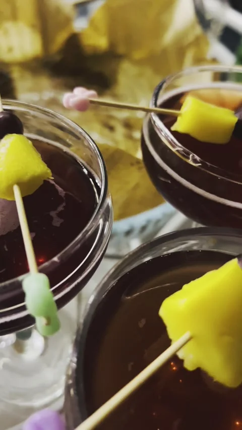 Multiple glasses of dark red cocktail with fruit garnish Stock Footage 345145676