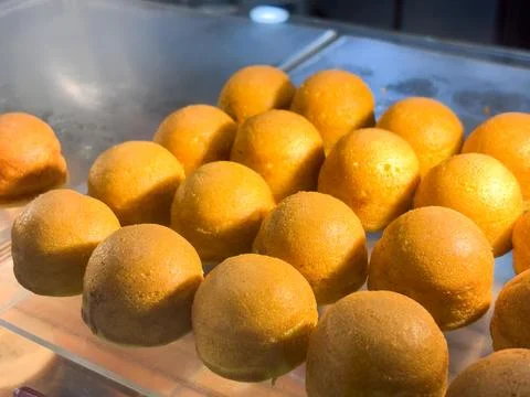 Multiple golden-orange, round mini sponge cakes or pastries Foto stock