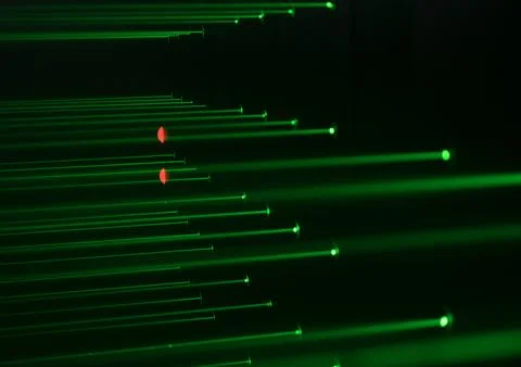 Multiple green laser beams crossing in dark space with red light reflections. Stock Photos