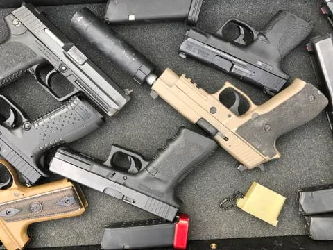 Multiple handguns lying on display table Stock Photos