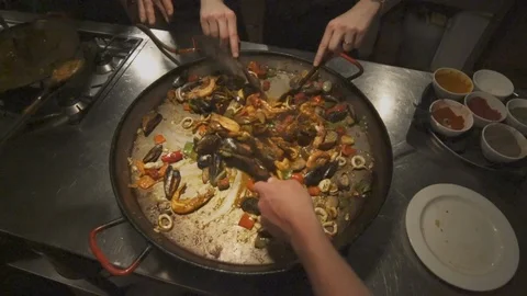 Multiple hands mixing paella before adding rice Video stock 100394056