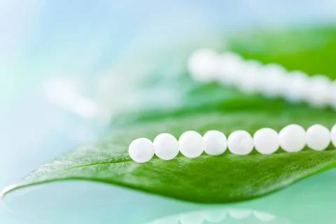 Multiple homeopathic pills on green leaves. Stock Photos