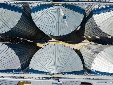 Multiple large grain silos arranged in a circular pattern on a farming site.  Photos