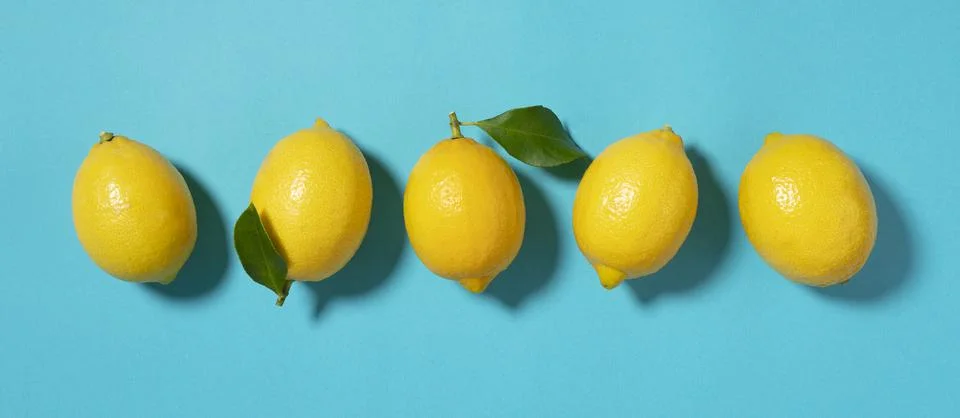 Multiple lemons placed on a blue background Stock Photos