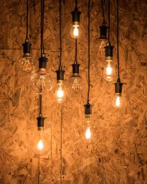 Multiple light bulbs hanging from ceiling, wooden background 스톡 사진