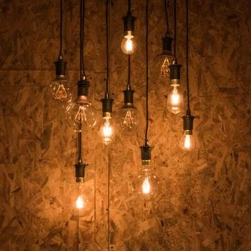 Multiple light bulbs hanging from ceiling, wooden background Stock Photos