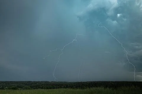 Multiple Lightning Strikes Over Forest During Intense Summer Storm Stock Photos