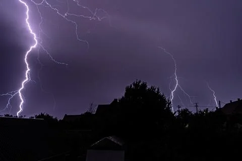 Multiple lightning strikes painting the sky purple on a summer evening duri.. Stock Photos