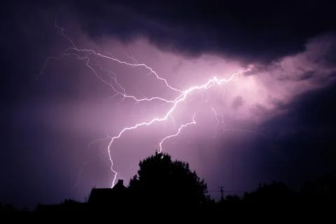 Multiple lightning strikes painting the sky purple on a summer evening duri.. Stock Photos