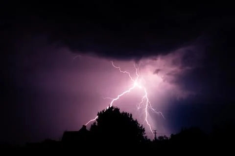 Multiple lightning strikes painting the sky purple on a summer evening duri.. Stock Photos