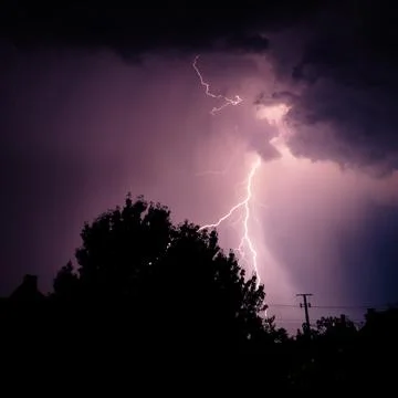 Multiple lightning strikes painting the sky purple on a summer evening duri.. Stock Photos