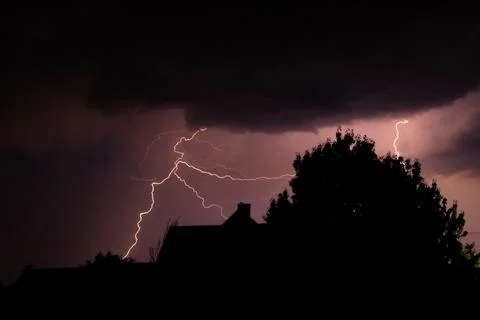 Multiple lightning strikes painting the sky purple on a summer evening duri.. Stock Photos