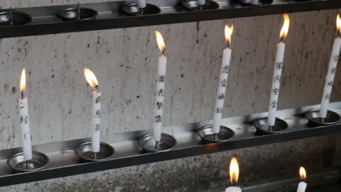 Multiple lit prayer candles with lucky spells on steel racks. Stock Footage 144906062