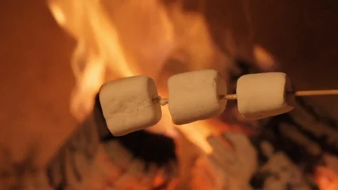 Multiple marshmallows extended over a fire to roast. Stock Footage 82541465