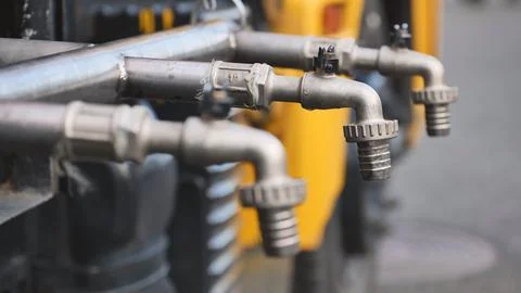 Multiple metal taps delivering water from system on a yellow utility truck Stock Photos