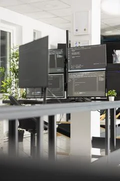 Multiple monitors displaying programming code in modern office 库存照片