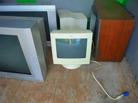 Multiple old computer monitors and TVs inside of electric waste container. Stock Photos